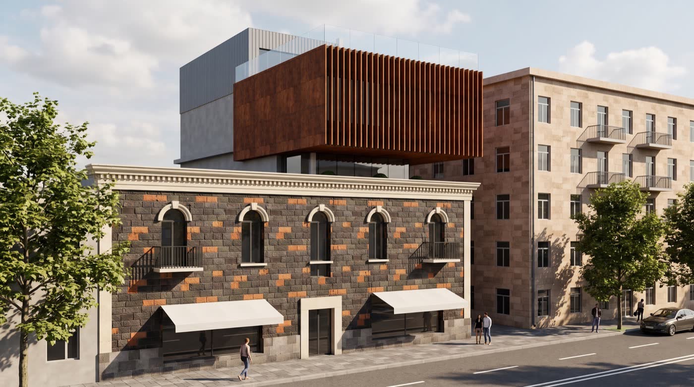 Isahakyan 42 from the street: the restored tuff facade with arched windows, and a corten steel volume with vertical fins rising above it.